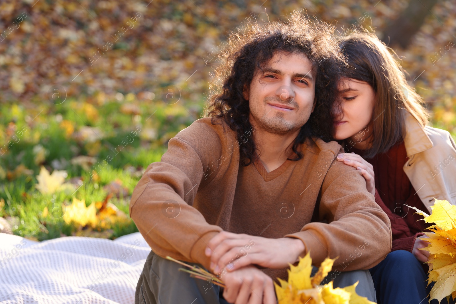 Photo of Happy young couple with dry leaves spending time together in autumn park, space for text. Dating agency