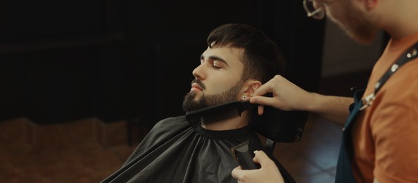 Professional hairdresser working with bearded client in barbershop, space for text. Banner design