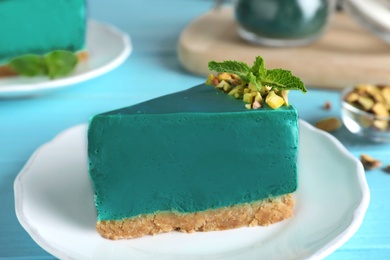 Piece of tasty spirulina cheesecake on light blue wooden table, closeup view