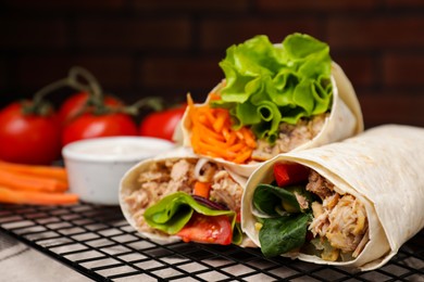 Photo of Delicious tortilla wraps with tuna on grill grate, closeup. Space for text