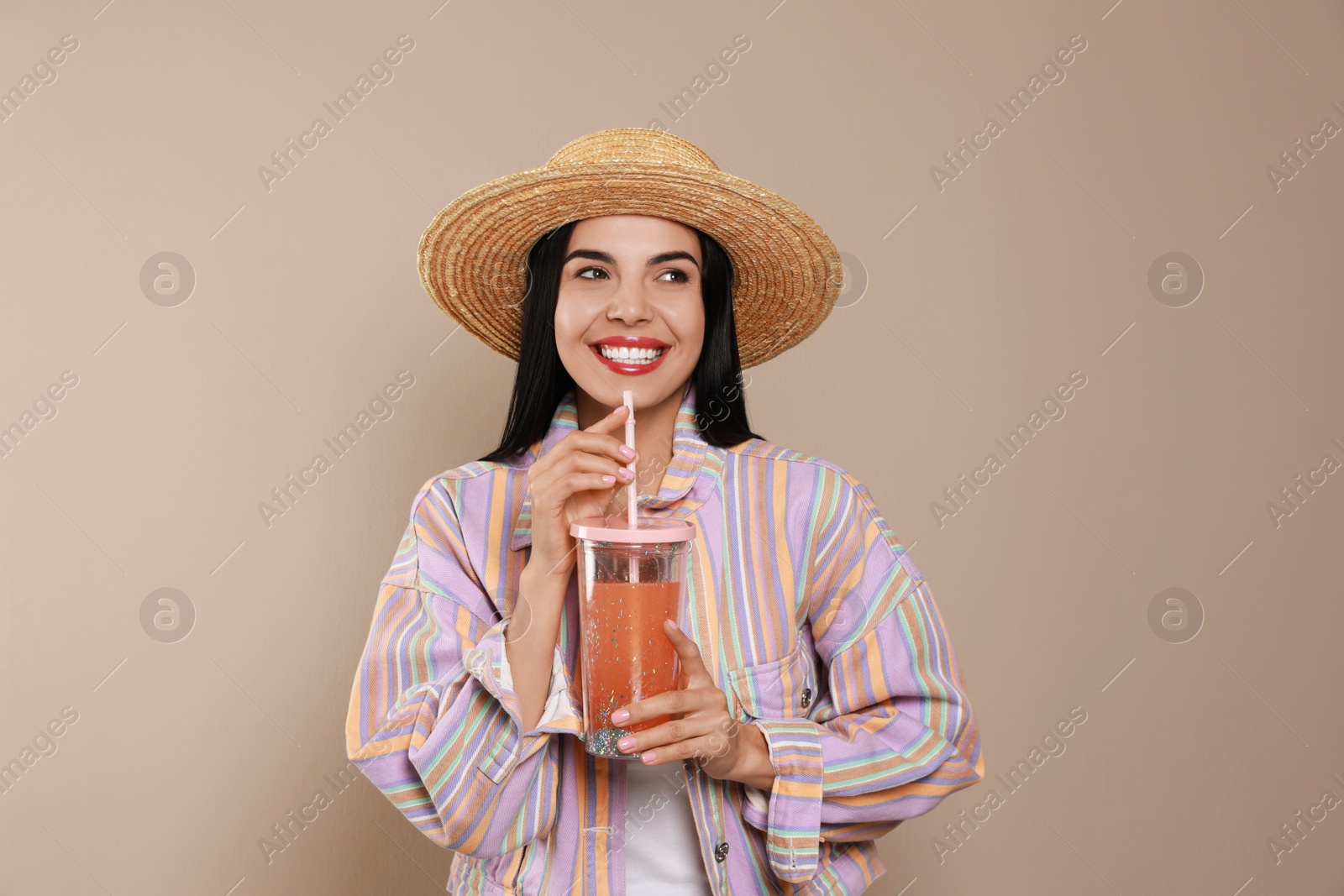 Photo of Beautiful young woman with straw hat and glass of refreshing drink on beige background