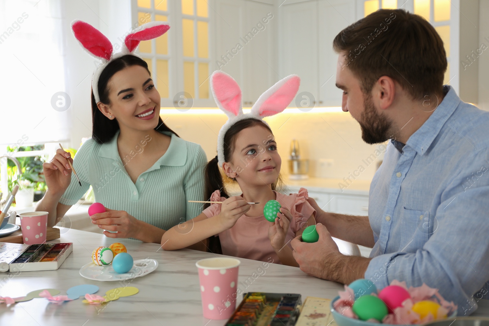 Photo of Happy family painting Easter eggs at table in kitchen