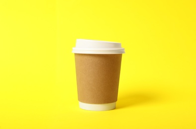 Takeaway paper coffee cup on yellow background