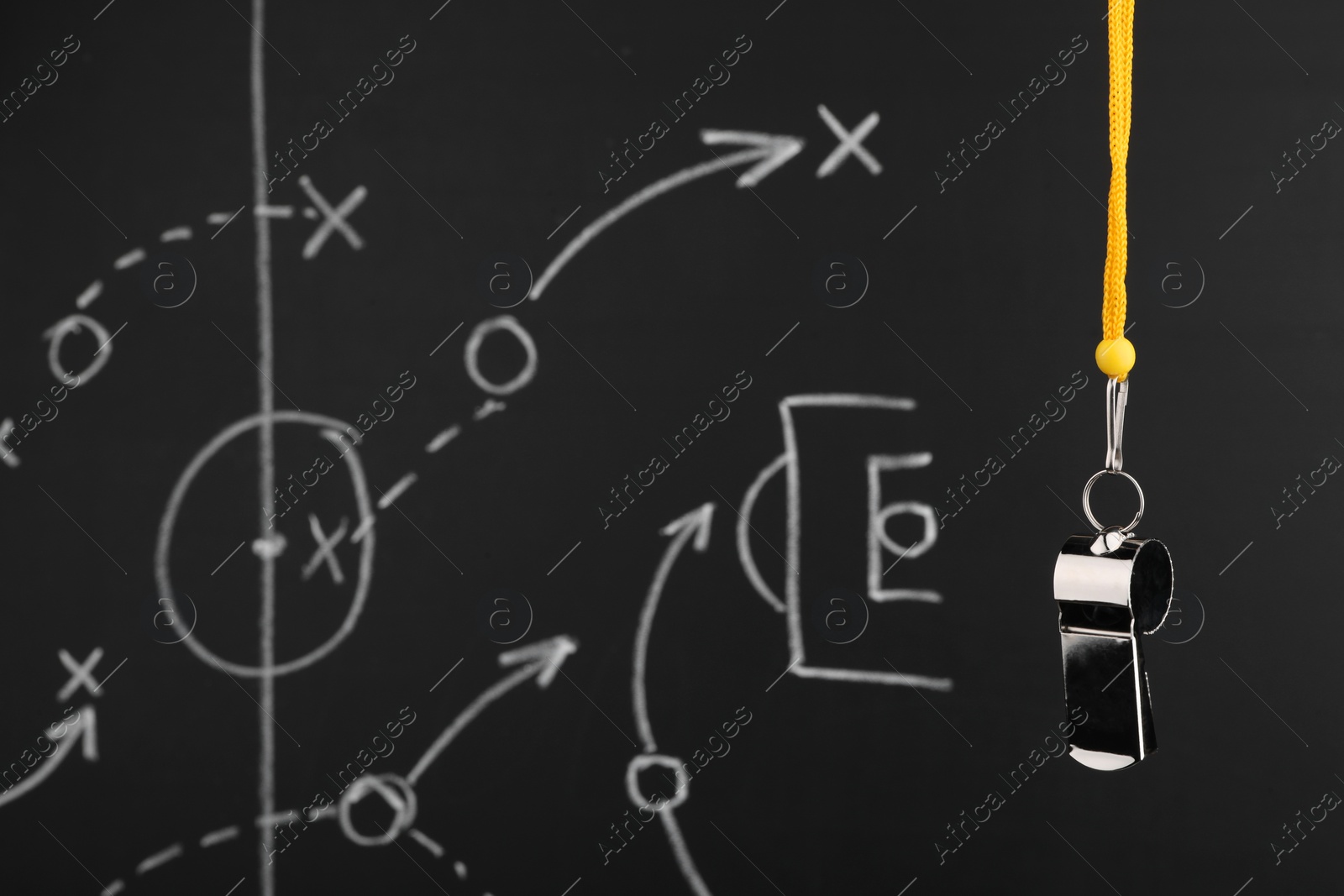Photo of Referee whistle against chalkboard with game scheme