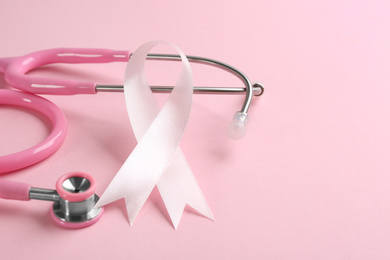 Photo of Pink ribbon and stethoscope on color background, closeup. Breast cancer concept