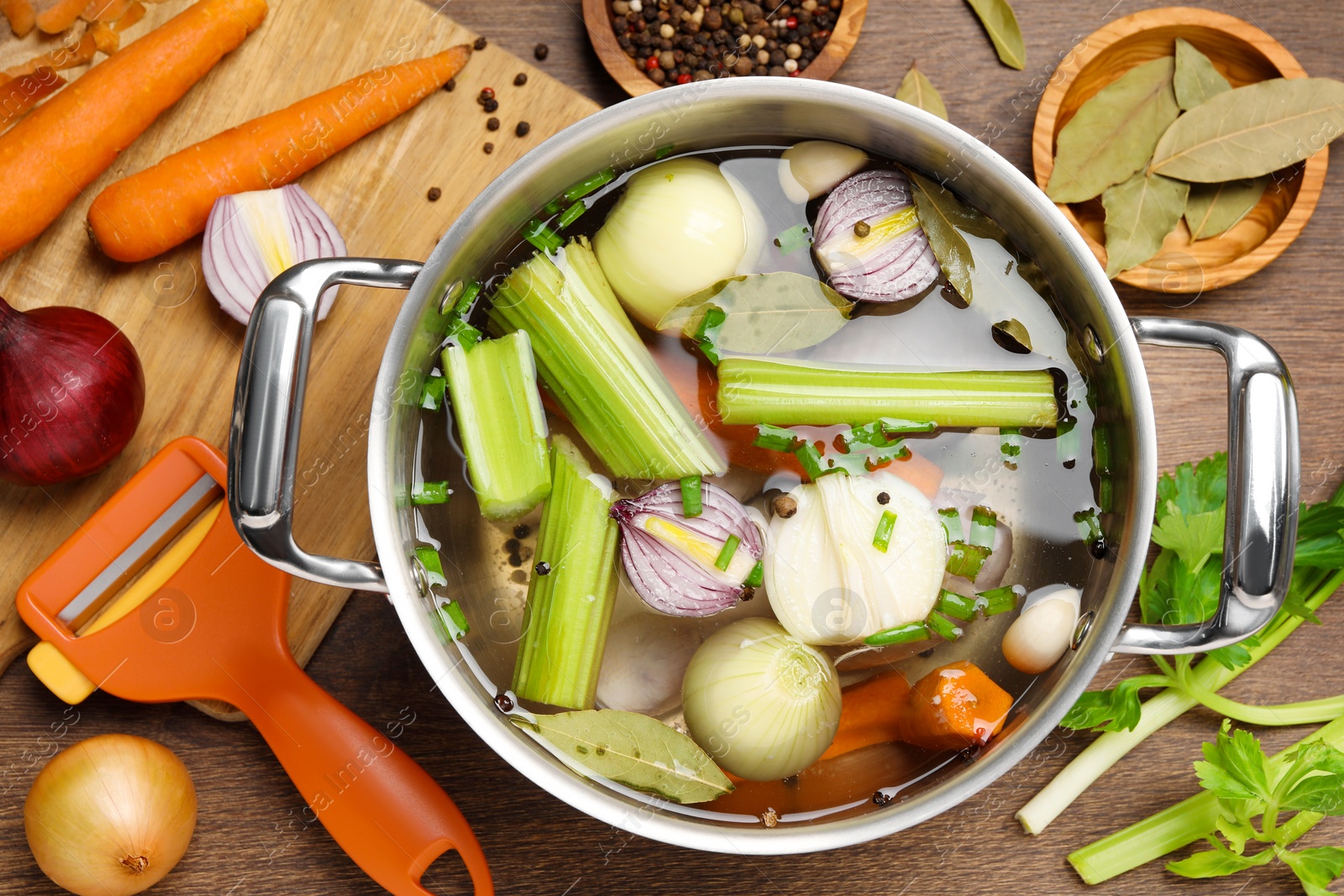 Photo of Pot and different ingredients for cooking tasty bouillon on wooden table, flat lay