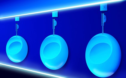 Image of Ceramic urinals in men's public restroom lit with UV blue light