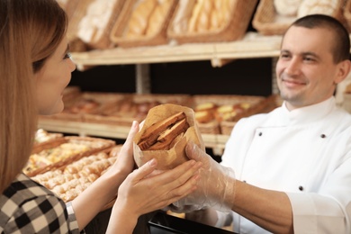 Woman buying tasty pastry in bakery shop