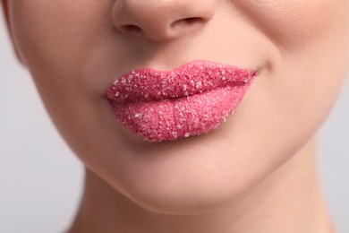 Photo of Young woman with beautiful lips covered in sugar on light background, closeup
