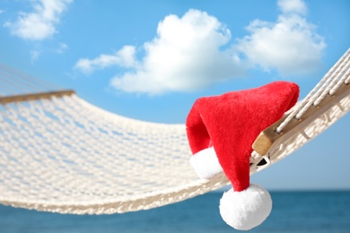 Photo of Rope hammock with Santa's hat on beach, closeup. Christmas vacation