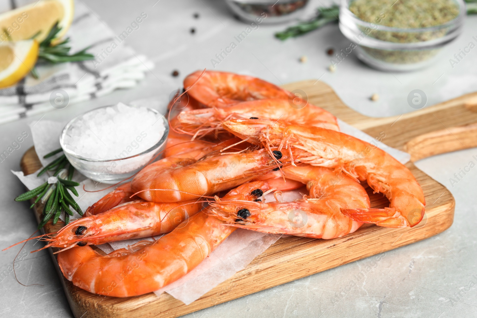 Photo of Delicious cooked shrimps with rosemary and salt on grey marble table