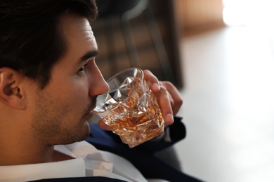 Photo of Young man with glass of whiskey indoors