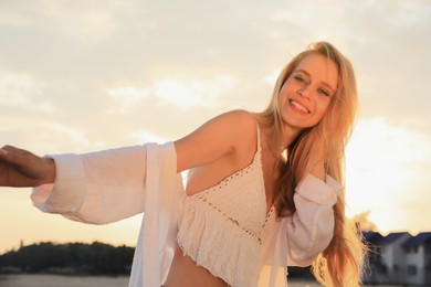 Photo of Happy young woman with beautiful blond hair outdoors at sunset