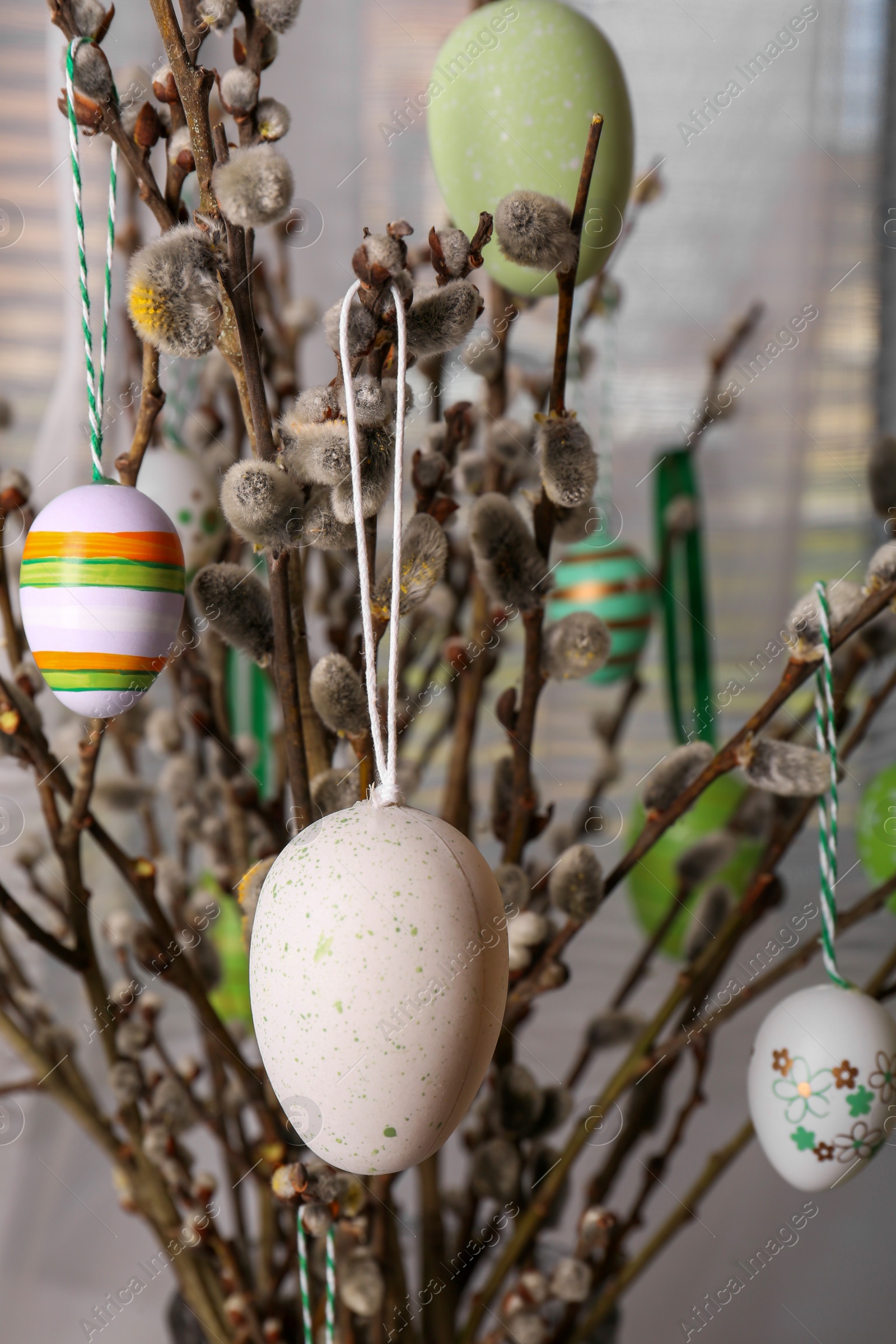 Photo of Beautiful willow branches with painted eggs indoors. Easter decor