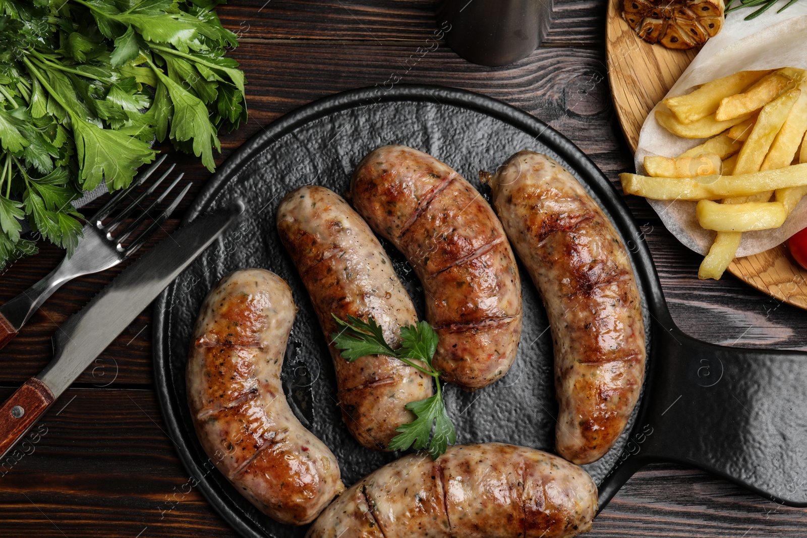 Photo of Tasty grilled sausages served on wooden table, flat lay