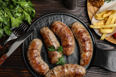 Tasty grilled sausages served on wooden table, flat lay