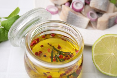 Photo of Tasty fish marinade in jar and lime on light tiled table, closeup