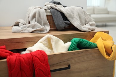 Cluttered chest of drawers indoors, closeup. Clothes in mess