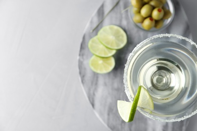 Glass of lemon drop martini cocktail with lime slice on grey table, top view. Space for text