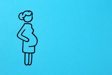 Photo of Pregnant woman figure drawn on light blue background, top view with space for text. Surrogacy concept