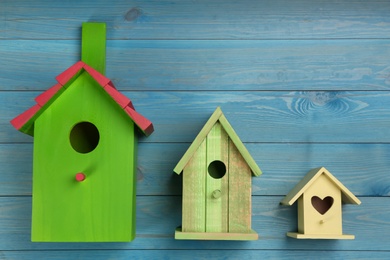 Three different bird houses on light blue wooden background