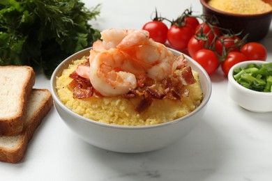 Fresh tasty shrimps, bacon and grits in bowl on white table, closeup