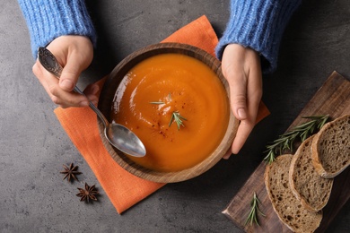 Woman eating tasty sweet potato soup at table, top view