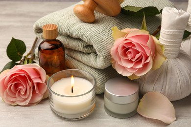 Photo of Composition with spa products, roses and candle on grey wooden table