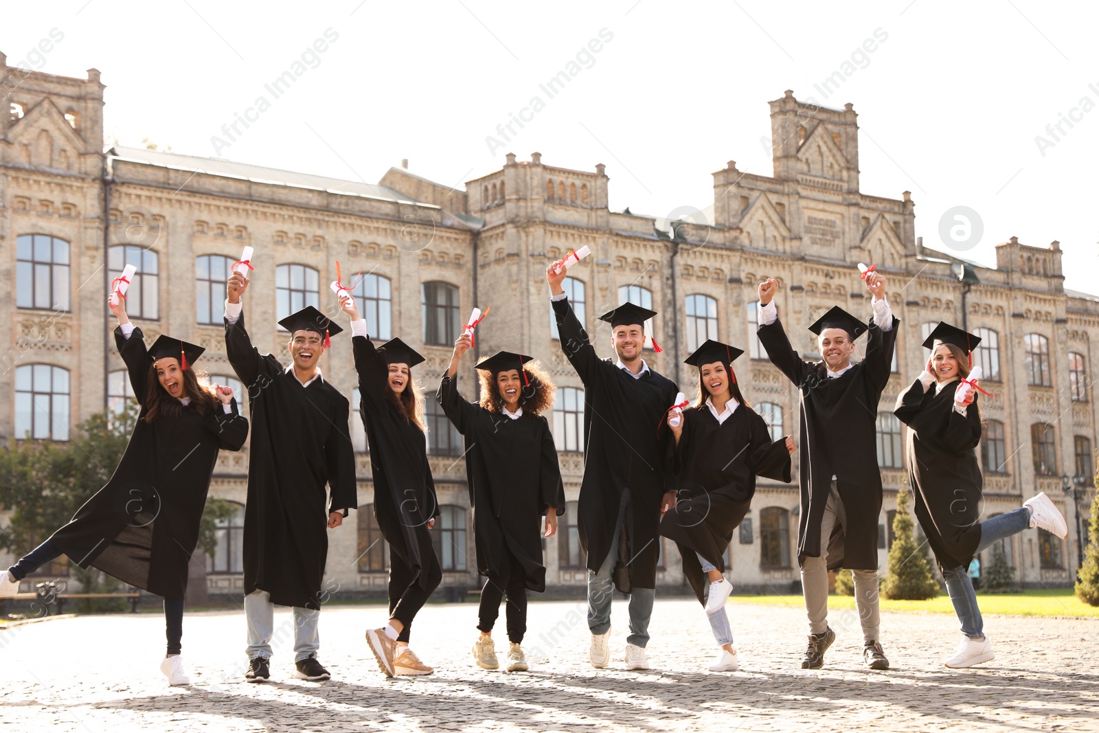 Photo of Happy students with diplomas outdoors. Graduation ceremony