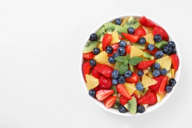 Photo of Yummy fruit salad in bowl on light blue background, top view. Space for text