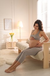 Pregnant young woman touching belly at home