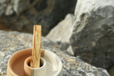 Photo of Palo santo stick on stone surface, closeup. Space for text