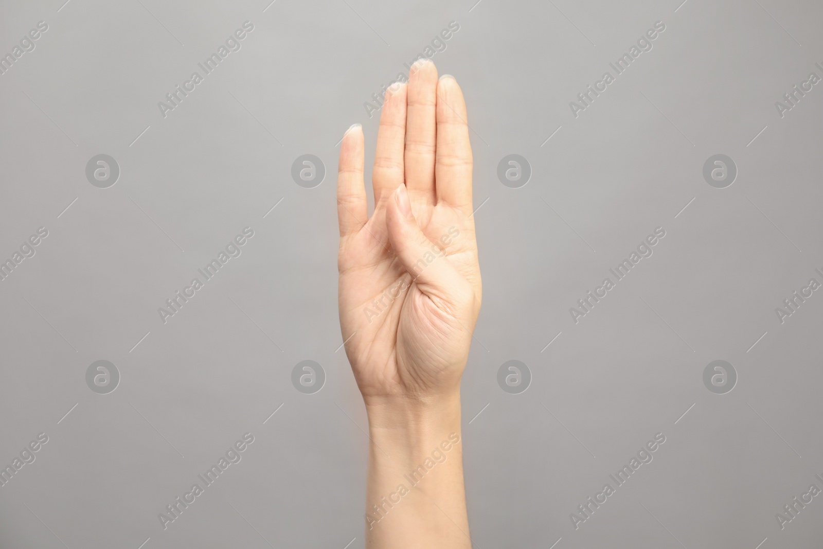 Photo of Woman showing B letter on grey background, closeup. Sign language