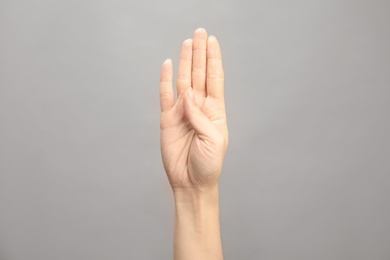 Photo of Woman showing B letter on grey background, closeup. Sign language