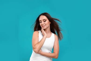 Beautiful young woman in casual outfit on turquoise background