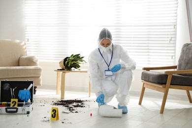 Photo of Investigator in protective suit working at crime scene indoors