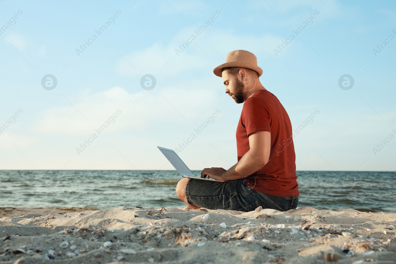 Photo of Man working with laptop on beach. Space for text