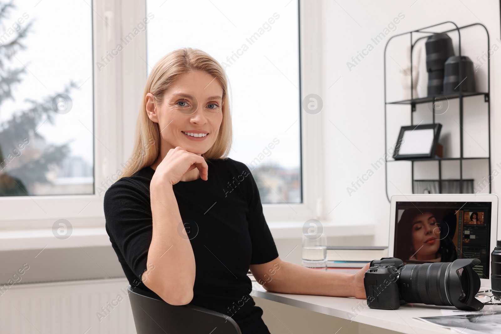 Photo of Professional photographer with digital camera at table in office