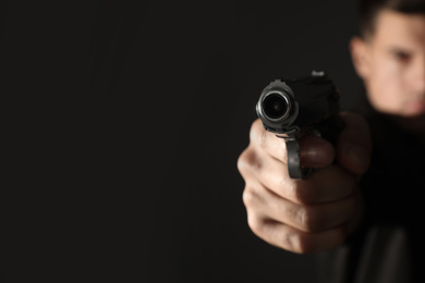 Photo of Professional killer on black background, focus on gun. Space for text