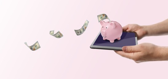 Image of Man holding tablet with piggy bank and flying dollar banknotes on pink background, banner design. Online banking