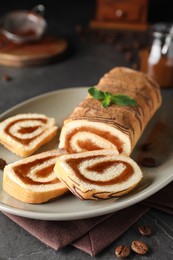 Photo of Tasty cake roll with jam and mint on grey table, closeup