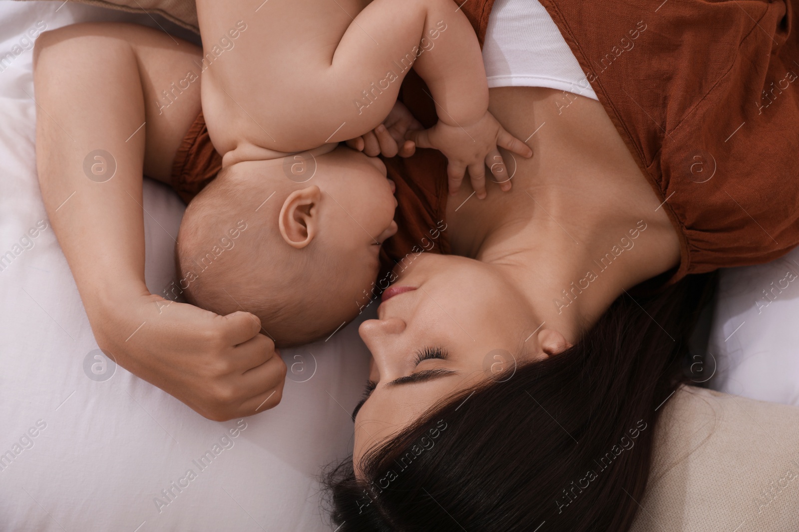 Photo of Mother with her cute baby sleeping on bed, top view