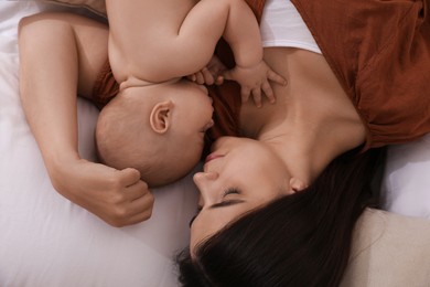 Photo of Mother with her cute baby sleeping on bed, top view