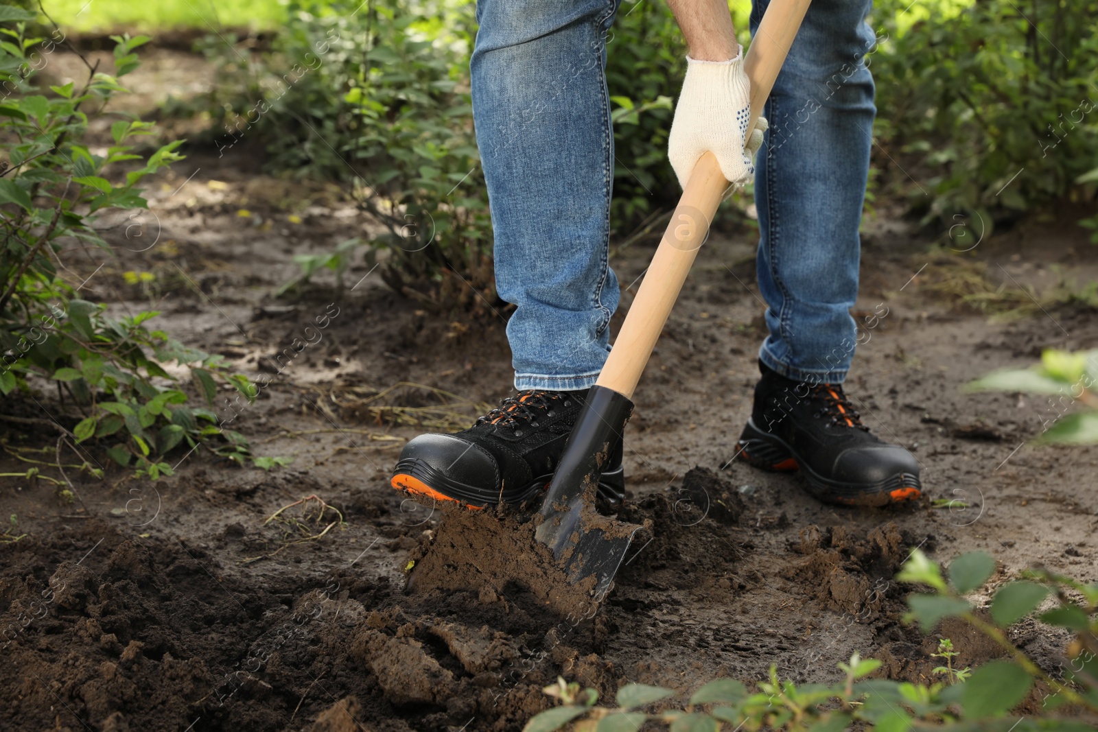 Photo of Worker digging soil with shovel outdoors, closeup