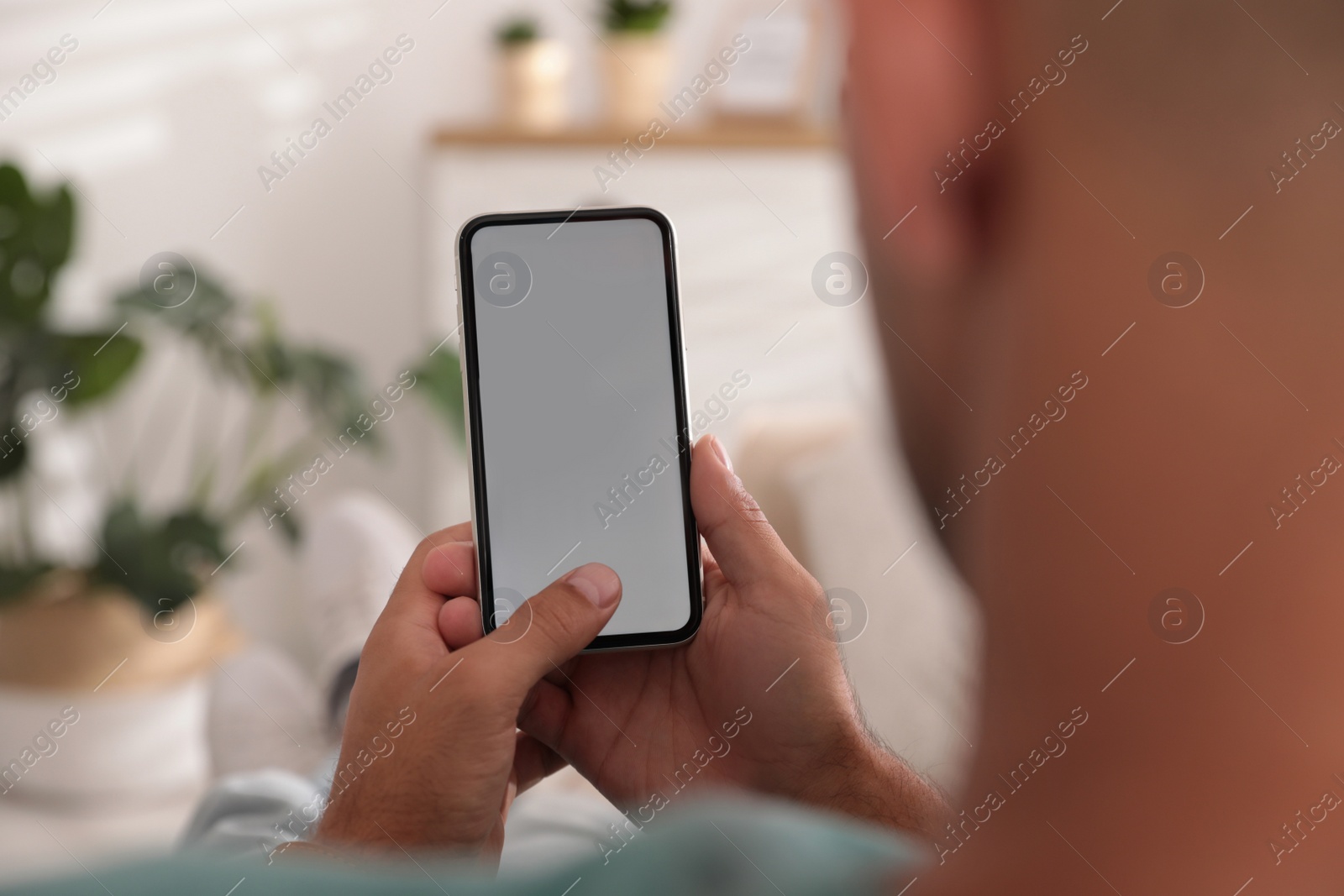 Photo of Man using mobile phone with empty screen indoors, closeup