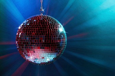 Image of Shiny disco ball under blue lights, space for text
