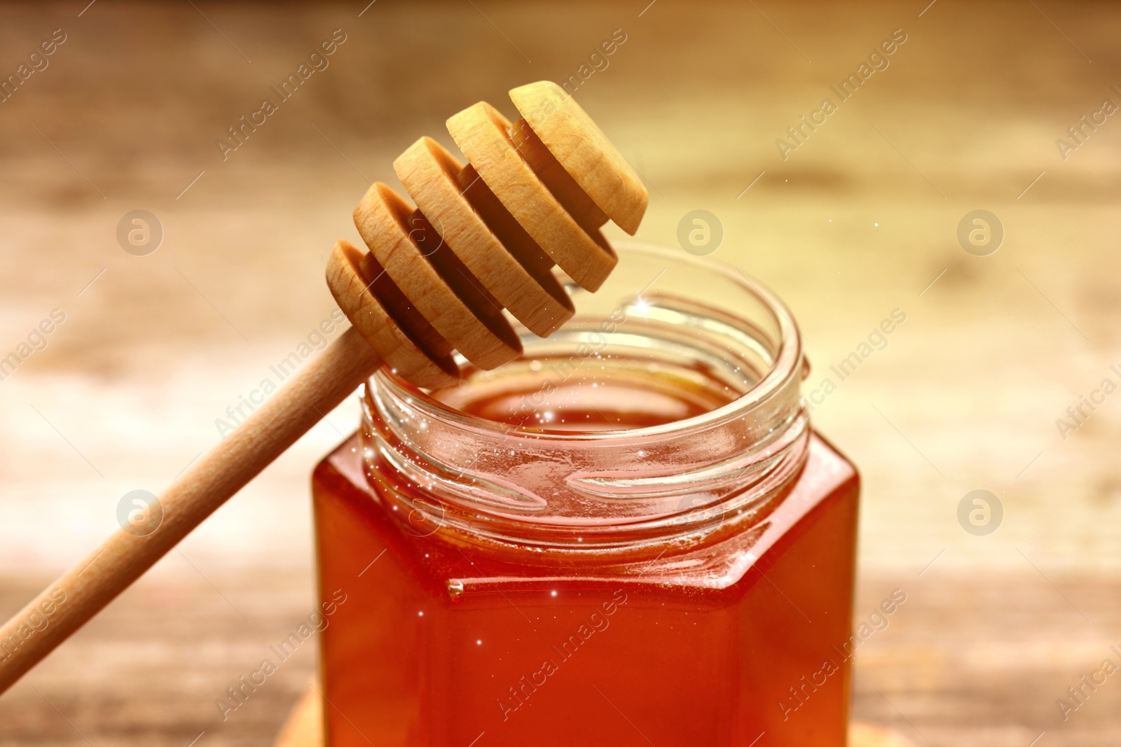 Image of Natural honey in glass jar and dipper under sunlight, closeup