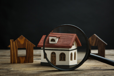 Photo of House models and magnifying glass on wooden table. Search concept