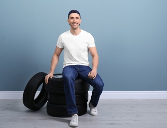 Young man with car tires on color wall background