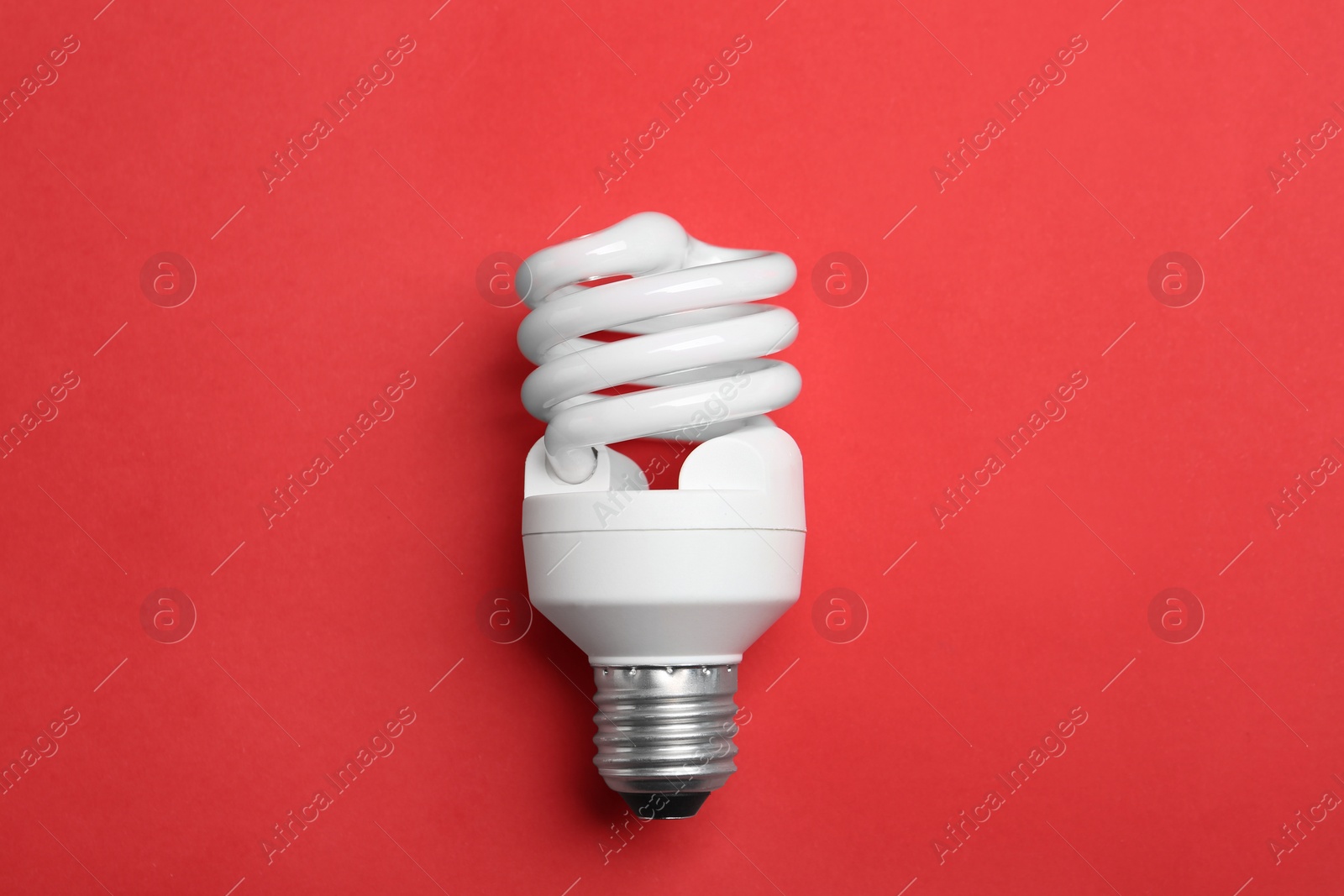 Photo of New fluorescent lamp bulb on red background, top view